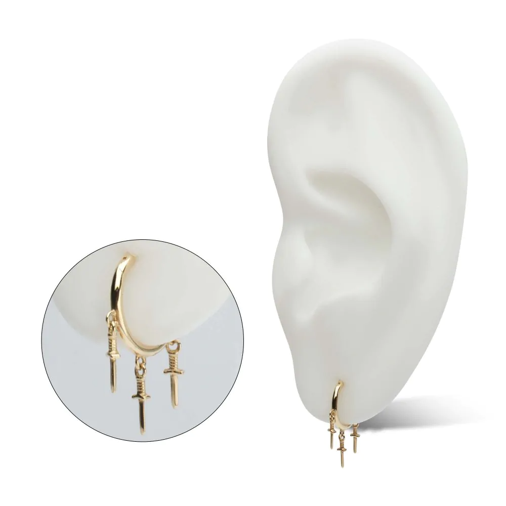 A 14k yellow gold clicker hoop earring with three danging daggers displayed in the lobe piercing of a model ear, with a separate close-up shot.