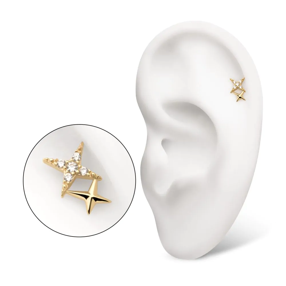 A 14k gold double star-shaped stud earring with two swarovski gems in the center, designed for body piercings. Displayed in the helix piercing of a model ear.