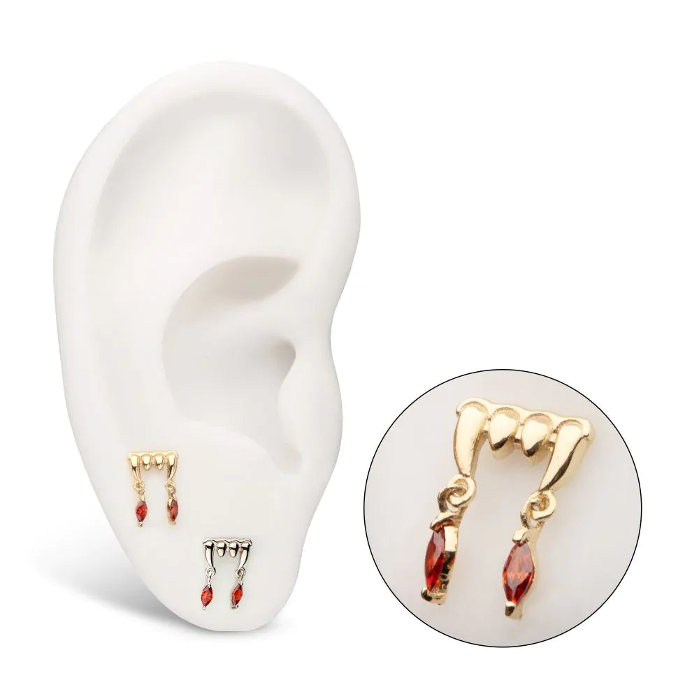 A piece of 14k gold body jewelry with dripping design and prong-set Swarovski crystals in red color, displayed from different angles.