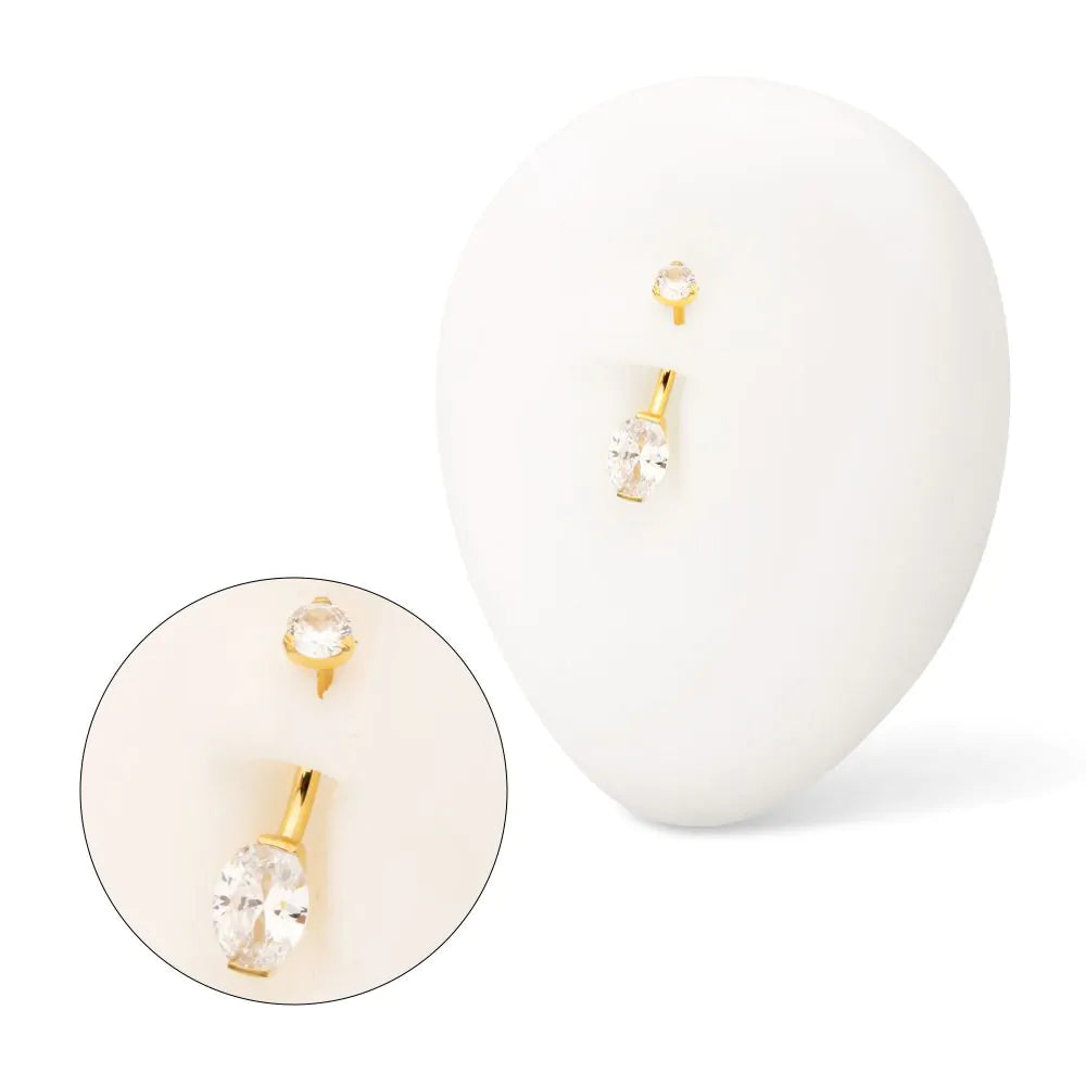 A gold-coloured navel barbell displayed in a model navel.